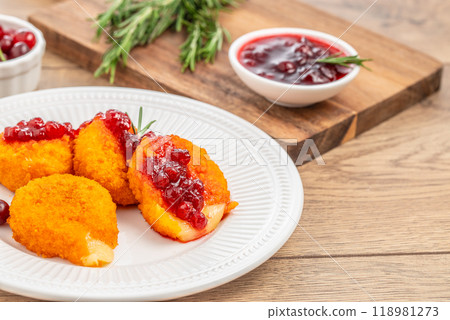 Baked or fried Camembert or brie cheese with cranberry and rosemary sauce on wooden Table 118981273