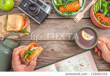 a man snacking on a sandwich and tea while planning a hiking route. travel concept 118981418