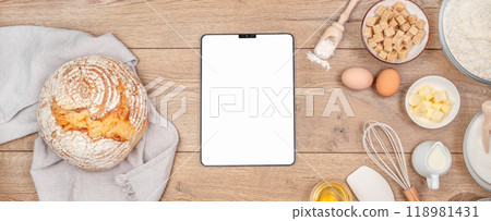 Digital tablet on kitchen table worktop on background with bread and utensils. Food recipes, online delivery, homemade food, cooking process 118981431