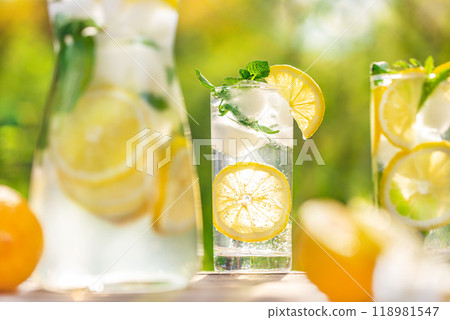 Lemonade drink with fresh lemon, mint and ice. Refreshing citrus cocktail in garden. summer concept Lemonade drink with fresh lemon, mint and ice. Refreshing citrus cocktail in garden. summer concept 118981547