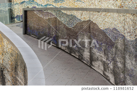 A sloping walkway leading down to a park in a high-rise building with cladding in the shape of an arch are decorated with colorful Stained glass scraps mosaic. 118981652