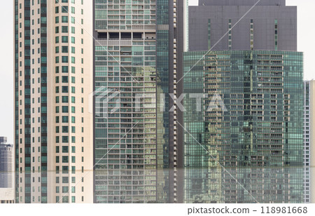 Architectural exterior of modern office building facade with blue sky and clouds reflection in windows. Architectural exterior of modern office building facade with blue sky and clouds reflection in windows. 118981668