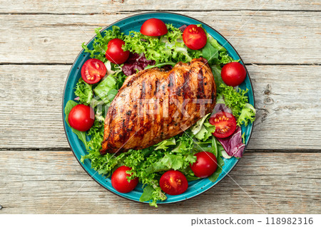 Grilled chicken breast ( fillet ) with lattuce salad and cherry tomatoes . Top view Grilled chicken breast ( fillet ) with lattuce salad and cherry tomatoes . Top view 118982316