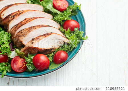 Grilled chicken breast ( fillet ) with lattuce salad and cherry tomatoes . Top view 118982321