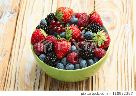 Mix of ripe colorful berries in bowl photography . Blueberry , strawberry , raspberry , blackberry and red currant . Top view 118982397