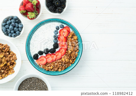 Healthy breakfast . Yogurt with berries ( strawberry , raspberry , blueberry , blackberry ) , granola and chia seeds . Top view Healthy breakfast . Yogurt with berries ( strawberry , raspberry , blueberry , blackberry ) , granola and chia seeds . Top view 118982412