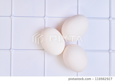 Three chicken bird eggs on a plastic checkered shelf in the fridge 118982927