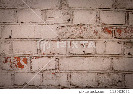 Weathered white brick wall with peeling paint revealing layers underneath in a rustic urban setting 118983021