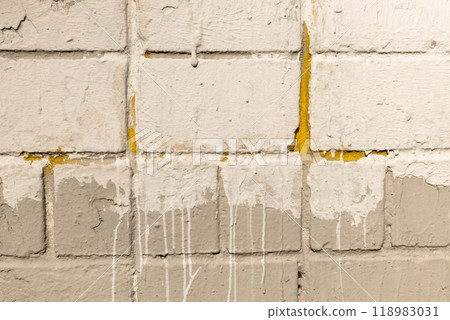 Textured wall with paint drips and worn surface in a dimly lit urban space showcasing age and character Textured wall with paint drips and worn surface in a dimly lit urban space showcasing age and character 118983031