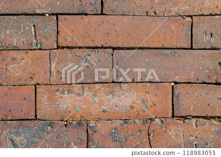Weathered brick wall with rich textures and earthy tones in warm daylight, showcasing rustic charm and history 118983055