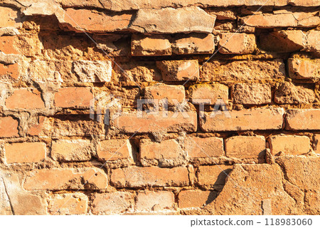 Textured bricks of an old wall with weathering in warm sunlight during the afternoon in a historic location 118983060