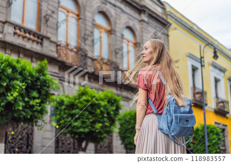 Female tourist walking through the colorful colonial streets of Puebla, Mexico. Travel, cultural exploration, and vibrant architecture concept 118983557