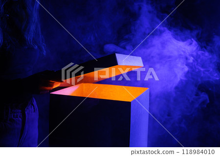 Man opens magic box with surprise on dark background, mystical box, surprise, halloween, monster box 118984010