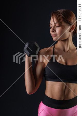 sporty girl doing exercises with dumbbells on black background, sport concept, healthy and beautiful body 118984011
