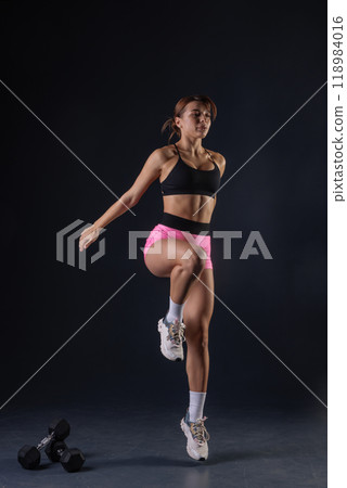 sporty girl doing exercises with dumbbells on black background, sport concept, healthy and beautiful body 118984016