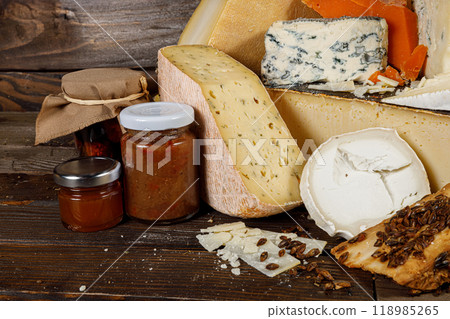 A beautiful Artisan Cheeses and Jams Display arranged elegantly on a Rustic Wooden Table 118985265