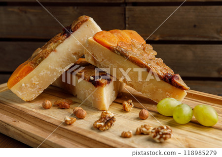 An Elegant Artisan Cheese Platter Accompanied by Nutty Grapes on a Rustic Wooden Board 118985279