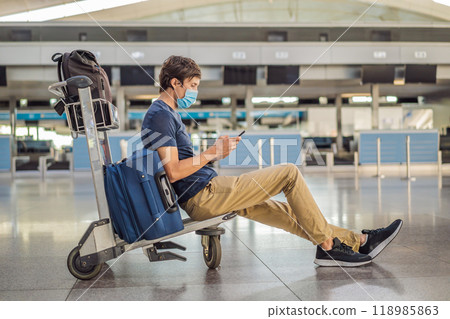 Man in mask at empty airport at check in in coronavirus quarantine isolation, returning home, flight cancellation, pandemic infection worldwide spread, travel restrictions and border shutdown 118985863