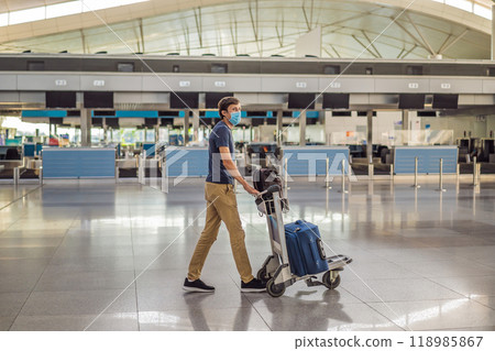 Man in mask at empty airport at check in in coronavirus quarantine isolation, returning home, flight cancellation, pandemic infection worldwide spread, travel restrictions and border shutdown 118985867