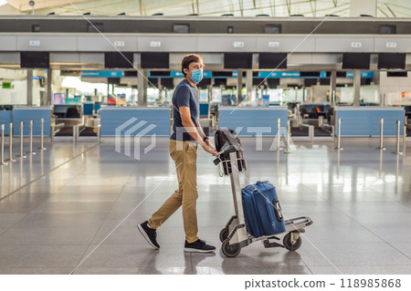 Man in mask at empty airport at check in in coronavirus quarantine isolation, returning home, flight cancellation, pandemic infection worldwide spread, travel restrictions and border shutdown Man in mask at empty airport at check in in coronavirus quarantine isolation, returning home, flight cancellation, pandemic infection worldwide spread, travel restrictions and border shutdown 118985868