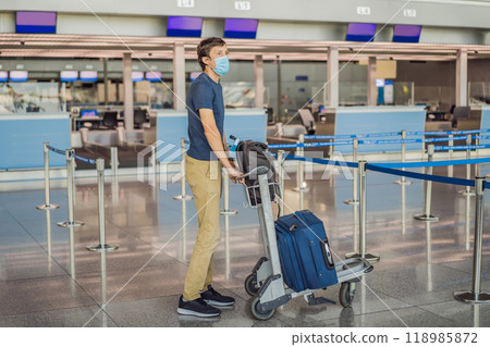 Man in mask at empty airport at check in in coronavirus quarantine isolation, returning home, flight cancellation, pandemic infection worldwide spread, travel restrictions and border shutdown Man in mask at empty airport at check in in coronavirus quarantine isolation, returning home, flight cancellation, pandemic infection worldwide spread, travel restrictions and border shutdown 118985872