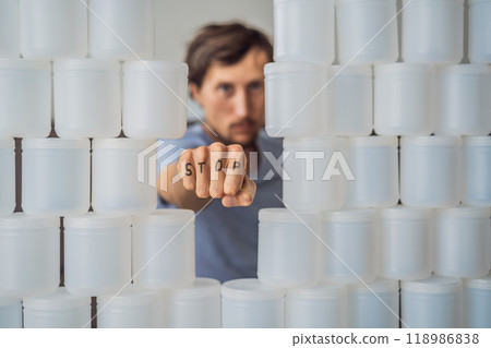 Man showing stop surrounded by many jars of yoghurt that he uses in a year. A huge amount of plastic food jars. Excessive consumption of plastic. Reduce, reuse, recycle 118986838