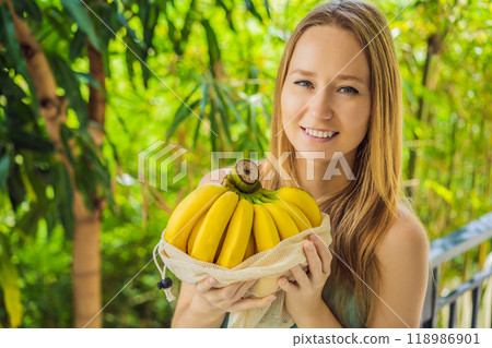 Banana in a reusable bag in the hands of a young woman. Zero waste concept, plastic free concept. Healthy clean eating diet and detox. Summer fruits 118986901