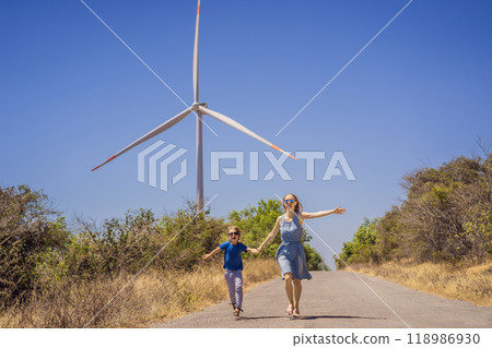 Alternative energy, wind farm and happy time with your family. Happy mother on the road with his son on vacation and escape to nature. Mother and son waving their arms like a windmill 118986930