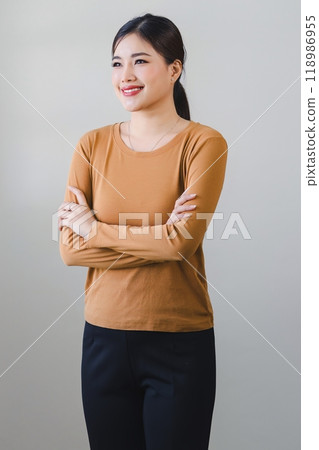 Confident asian woman with friendly smile stands with arms crossed isolated on white background. Confident asian woman with friendly smile stands with arms crossed isolated on white background. 118986955