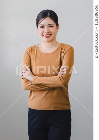 Confident asian woman with friendly smile stands with arms crossed isolated on white background. 118986956