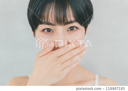 Young woman covering her mouth with her hand 118987185