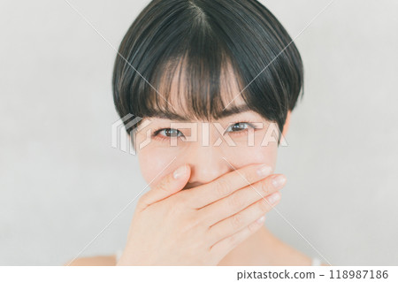 Young woman covering her mouth with her hand Young woman covering her mouth with her hand 118987186