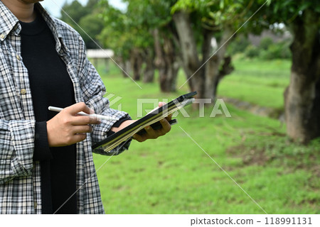 Farmer using digital tablet for recording data or conducting an assessment of the agricultural environment 118991131