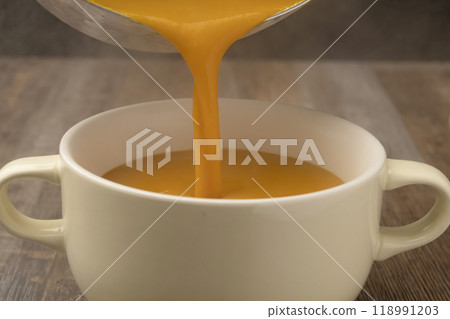 Pumpkin potage poured from pot into soup cup Pumpkin potage poured from pot into soup cup 118991203