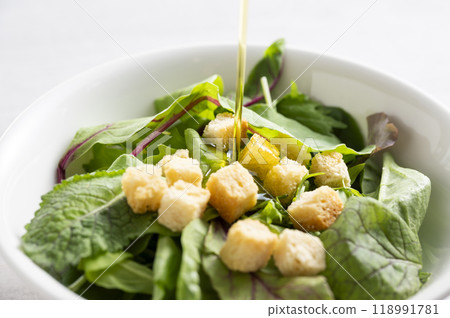 Drizzle olive oil over baby leaf salad 118991781