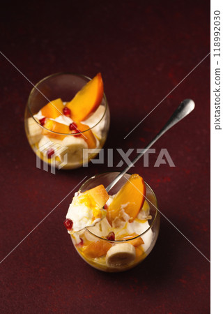 Delicious dessert with tropical fruits in glasses on a burgundy background Delicious dessert with tropical fruits in glasses on a burgundy background 118992030