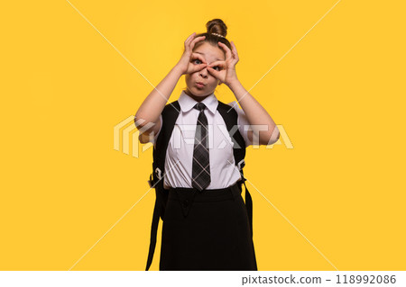 Teen girl making playful glasses gesture with hands 118992086