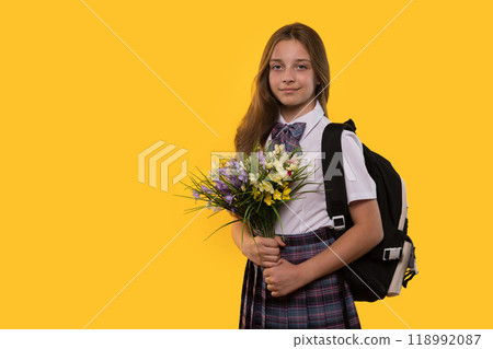 Schoolgirl in uniform holds bouquet of flowers 118992087