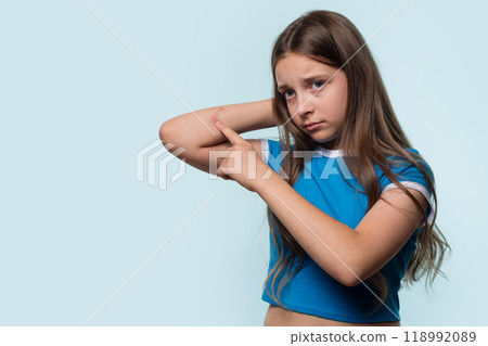 Young girl pointing at a cut on elbow, looking worried 118992089