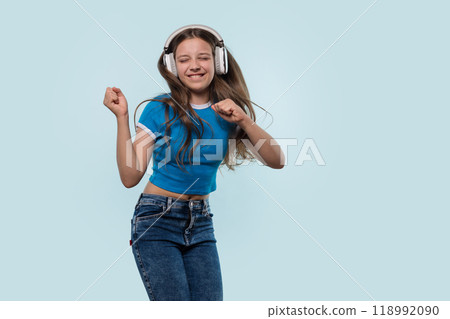 Girl wearing headphones dances joyfully while listening to music. 118992090