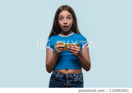 Girl looking surprised while holding smartphone, expressing shock 118992091