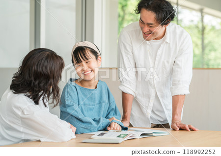 Mother and father watching their daughter study (family, homework, exam, studying for exam) Mother and father watching their daughter study (family, homework, exam, studying for exam) 118992252