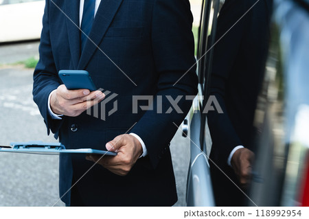 Businessman assessing a car Businessman assessing a car 118992954