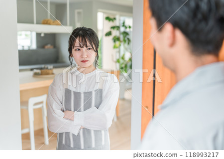 Wife, young Asian woman, looking at her husband with a displeased face when he returns home 118993217