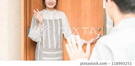 一位年輕的亞洲女性/妻子在早上上班時微笑著送行 一位年輕的亞洲女性/妻子在早上上班時微笑著送行 118993251