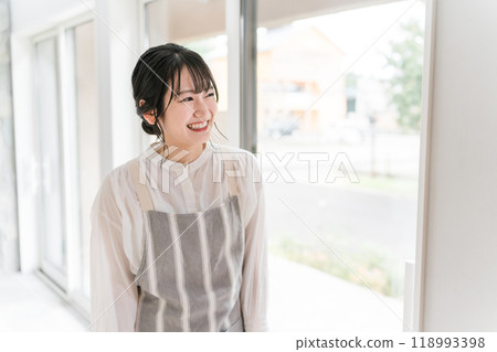 一位年輕的亞洲女性在家穿著圍裙 一位年輕的亞洲女性在家穿著圍裙 118993398