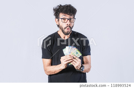 Amazed man with money in hand, man in glasses amazed with banknotes in hand, concept of man earning money Amazed man with money in hand, man in glasses amazed with banknotes in hand, concept of man earning money 118993524