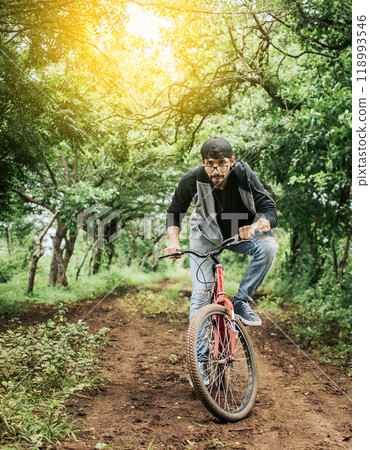 A guy riding a bike in the countryside, Person riding a bike in the countryside, Portrait of a guy in cap riding a bike on a country road, Bicyclist person on his bike on a country road forest. 118993546