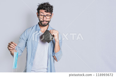 People deciding which surgical mask to wear, Person deciding to wear a medical mask in an isolated context, Isolated man deciding which medical mask to wear 118993672