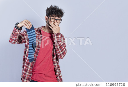 Handsome man with a smelly sock in his hand holding his nose isolated. Person with a stinky sock in his hand, concept of smelly socks and uncleanliness Handsome man with a smelly sock in his hand holding his nose isolated. Person with a stinky sock in his hand, concept of smelly socks and uncleanliness 118993728